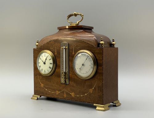 fig 2. An Edwardian mahogany desk compendium featuring an inlaid floral swag motif, central thermometer, clock dial, barometer dial, and top brass handle.