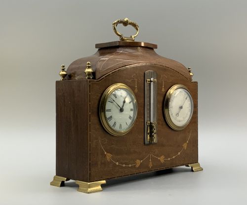 fig 3. An Edwardian mahogany desk compendium featuring an inlaid floral swag motif, central thermometer, clock dial, barometer dial, and top brass handle.