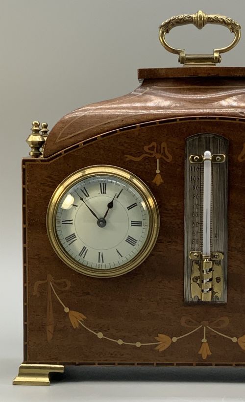 fig 7. An Edwardian mahogany desk compendium featuring an inlaid floral swag motif, central thermometer, clock dial, barometer dial, and top brass handle.