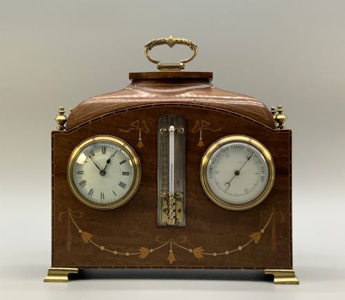 fig 8. An Edwardian mahogany desk compendium featuring an inlaid floral swag motif, central thermometer, clock dial, barometer dial, and top brass handle.