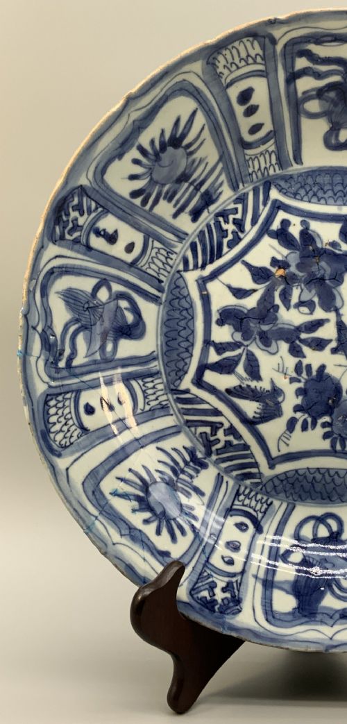 fig 5. A circular 16th-century Chinese Kraak porcelain charger decorated in cobalt blue underglaze featuring a central floral scene surrounded by a panelled foliate rim.