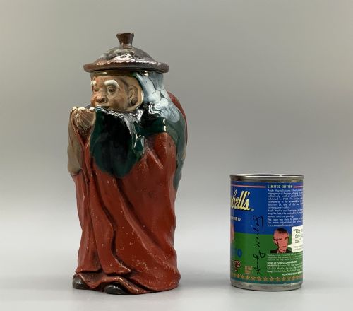 fig 1. An antique Japanese Sumida Gawa lidded pottery jug sculpted in the form of a robed figure with red attire, green glaze drips, and a matching fitted lid.