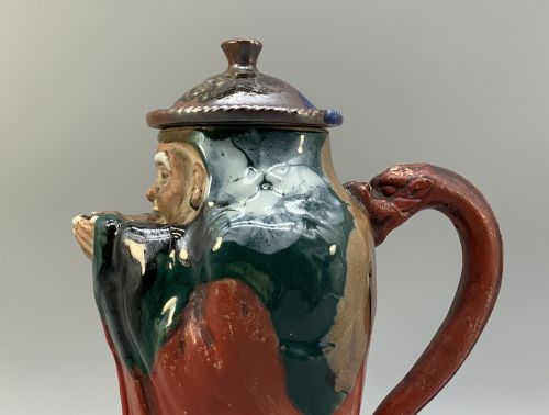 fig 7. An antique Japanese Sumida Gawa lidded pottery jug sculpted in the form of a robed figure with red attire, green glaze drips, and a matching fitted lid.