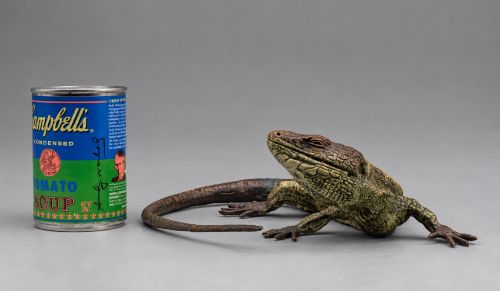 fig 2. An antique cold-painted bronze sculpture depicting a realistic lizard with textured yellow and brown skin, blue accents, and a long curved tail.
