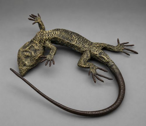 fig 8. An antique cold-painted bronze sculpture depicting a realistic lizard with textured yellow and brown skin, blue accents, and a long curved tail.