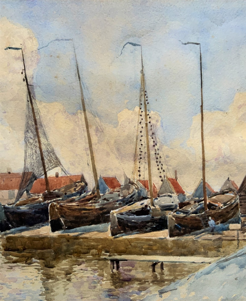 A 19th-century watercolour painting depicting several wooden sailing boats docked at a boat yard alongside buildings, housed within a wide gilt mount and thin gilt frame. View V