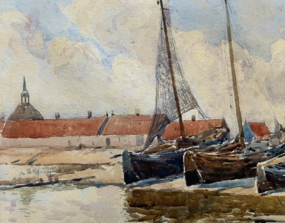 A 19th-century watercolour painting depicting several wooden sailing boats docked at a boat yard alongside buildings, housed within a wide gilt mount and thin gilt frame. View VII
