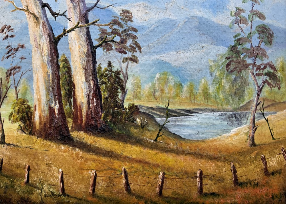 A mid-century oil landscape painting depicting tall gum trees beside a lake against blue mountains, framed in a gilt and fabric-lined wooden frame. View III