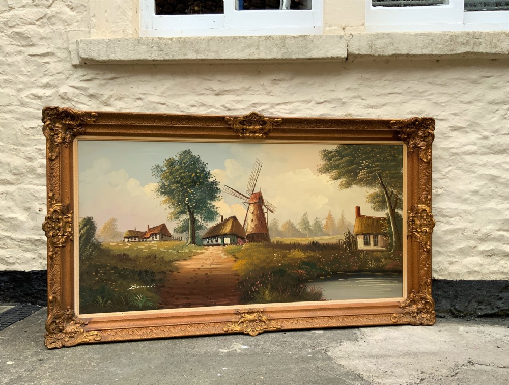 A horizontal oil painting depicting a rural Dutch scene with a tall windmill, thatched cottages, and a calm pond, framed in an ornate gilded frame. View II