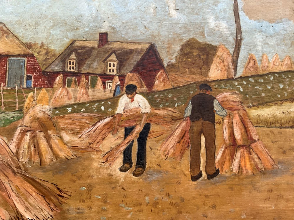 A mid-20th-century naive oil painting depicting agricultural workers gathering hay bales in a field beside a timber windmill, thatched cottages, and trees, presented in a gilt frame. View IX