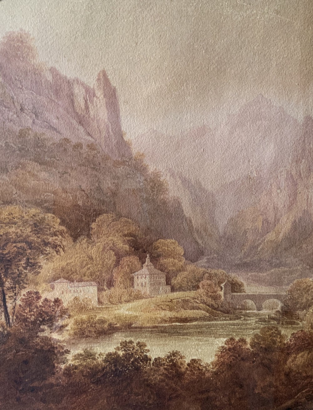 An antique 19th-century watercolour painting depicting a mountainous river landscape set within an arched cream mount and gilt wooden frame. View VII