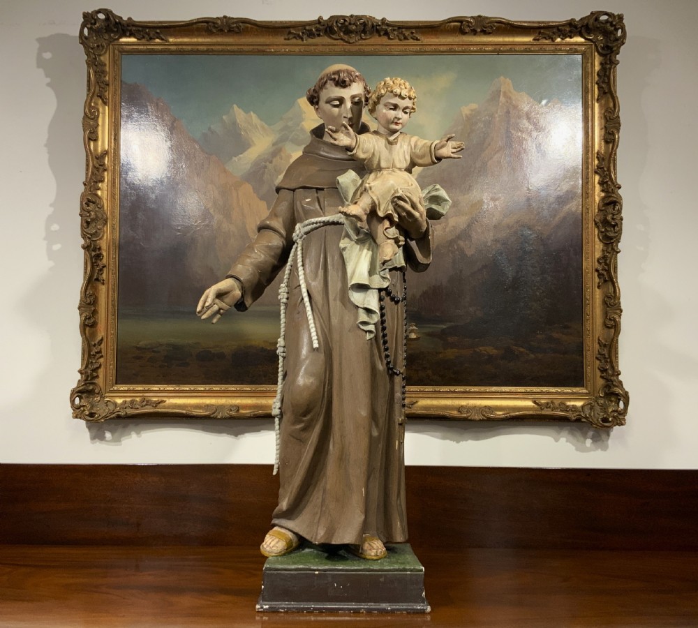 A carved polychrome wood statue depicting a saint in a brown robe holding the infant Jesus. View II