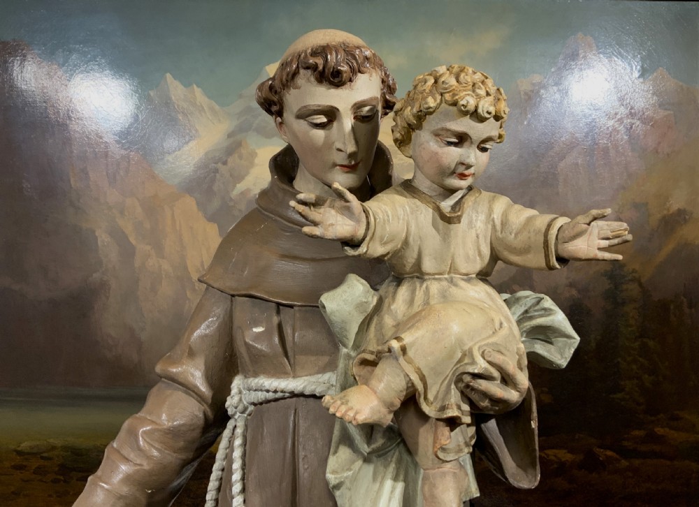 A carved polychrome wood statue depicting a saint in a brown robe holding the infant Jesus. View III