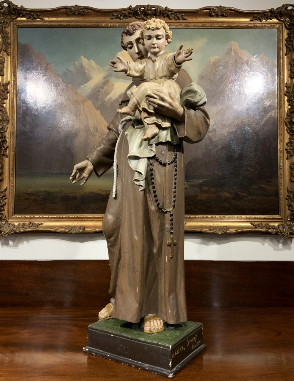 A carved polychrome wood statue depicting a saint in a brown robe holding the infant Jesus. View V