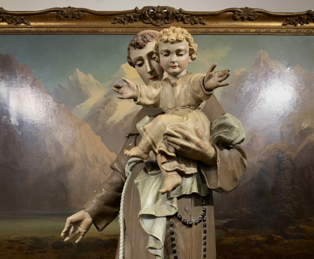 A carved polychrome wood statue depicting a saint in a brown robe holding the infant Jesus. View VI
