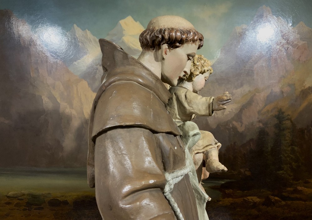 A carved polychrome wood statue depicting a saint in a brown robe holding the infant Jesus. View XI