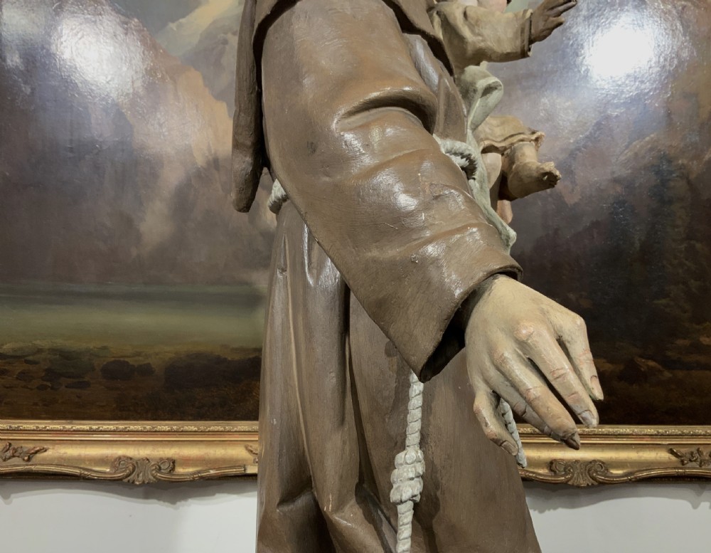 A carved polychrome wood statue depicting a saint in a brown robe holding the infant Jesus. View XII