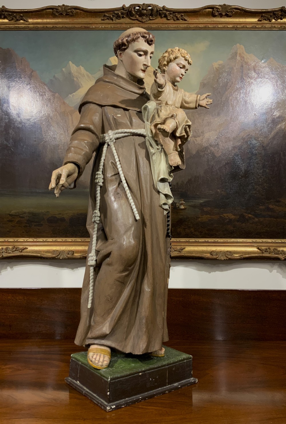 A carved polychrome wood statue depicting a saint in a brown robe holding the infant Jesus. View XIII