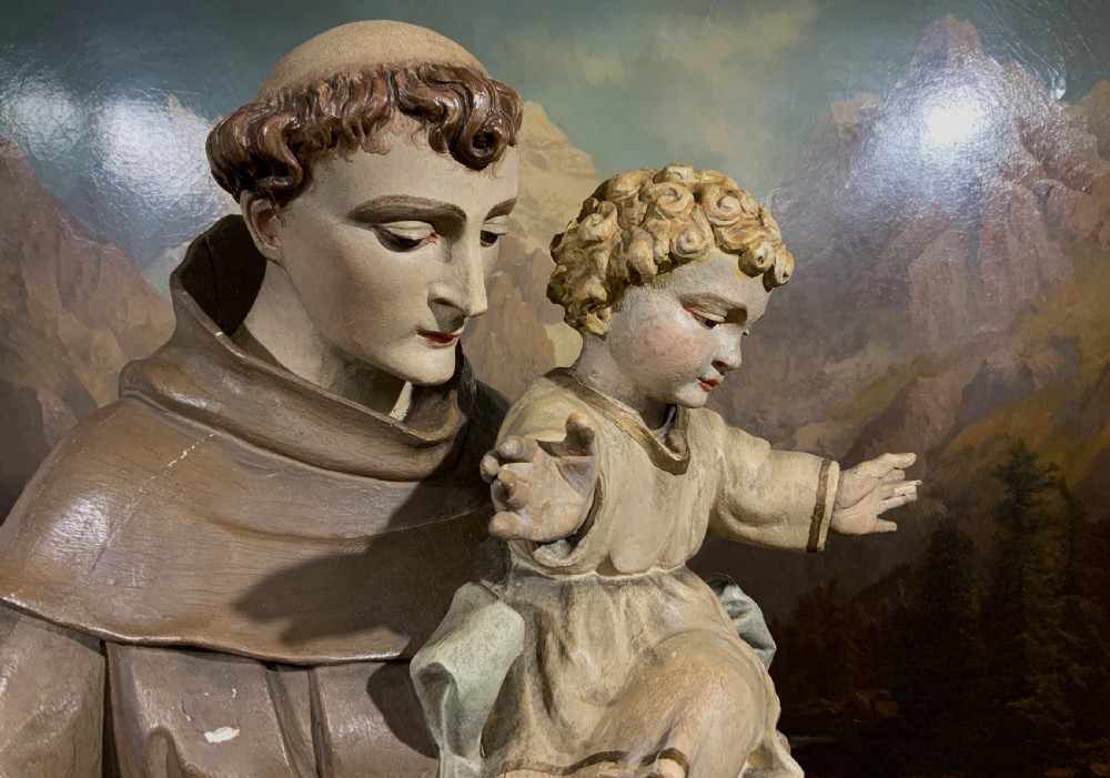 A carved polychrome wood statue depicting a saint in a brown robe holding the infant Jesus. View XIV