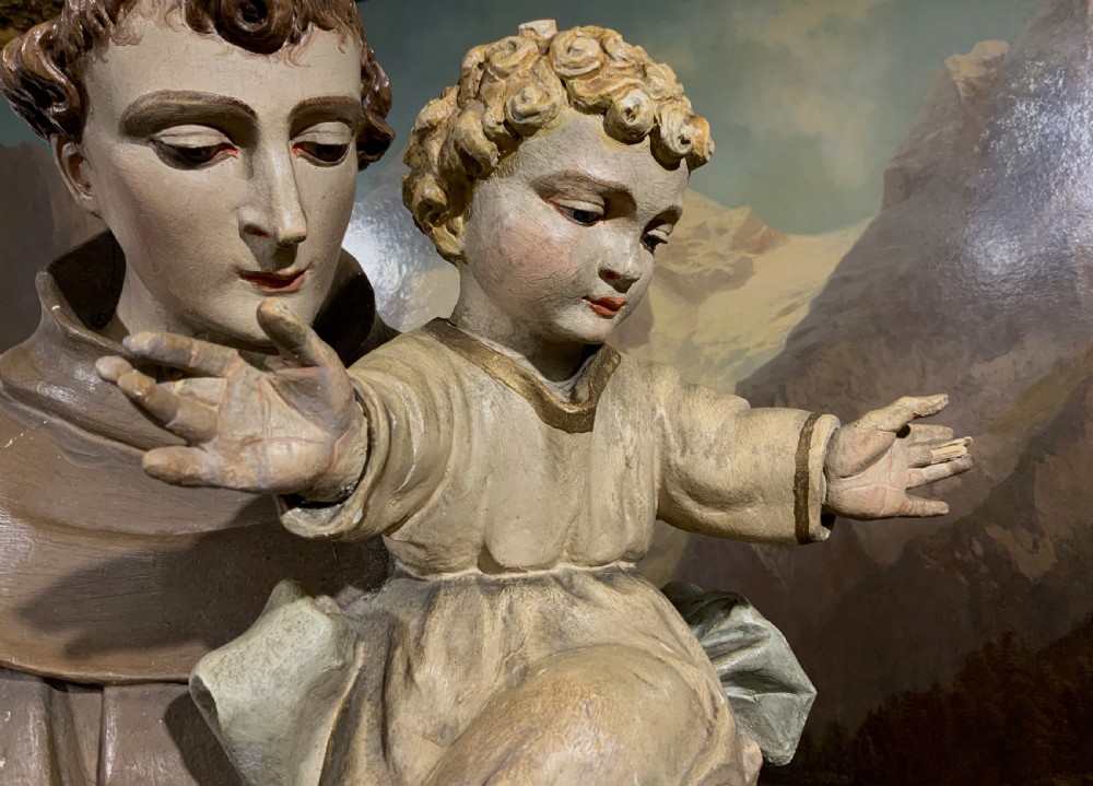 A carved polychrome wood statue depicting a saint in a brown robe holding the infant Jesus. View XV