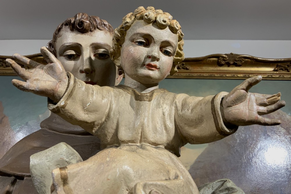 A carved polychrome wood statue depicting a saint in a brown robe holding the infant Jesus. View XVII