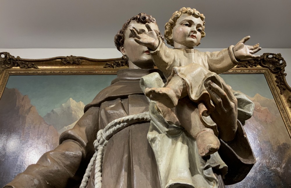 A carved polychrome wood statue depicting a saint in a brown robe holding the infant Jesus. View XIX