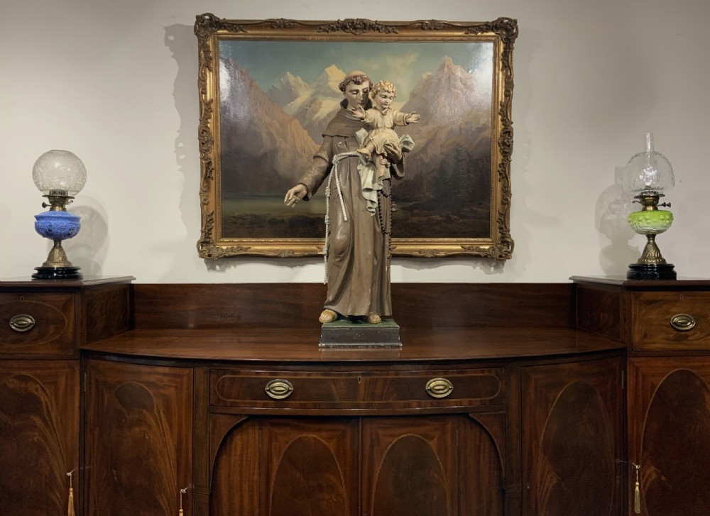 A carved polychrome wood statue depicting a saint in a brown robe holding the infant Jesus. View XXI