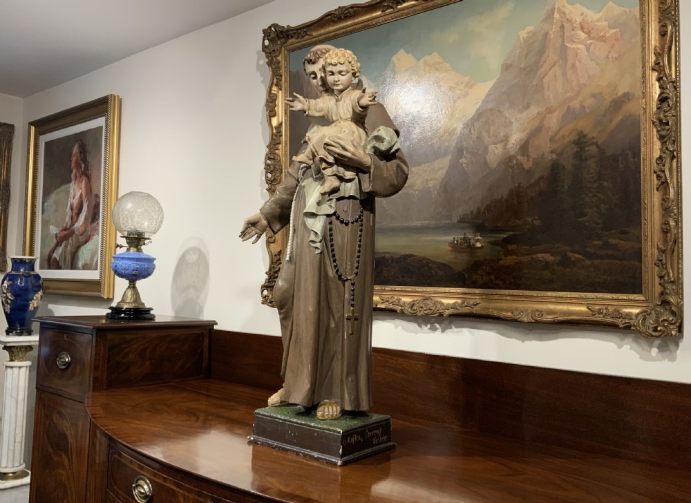 A carved polychrome wood statue depicting a saint in a brown robe holding the infant Jesus. View XXII