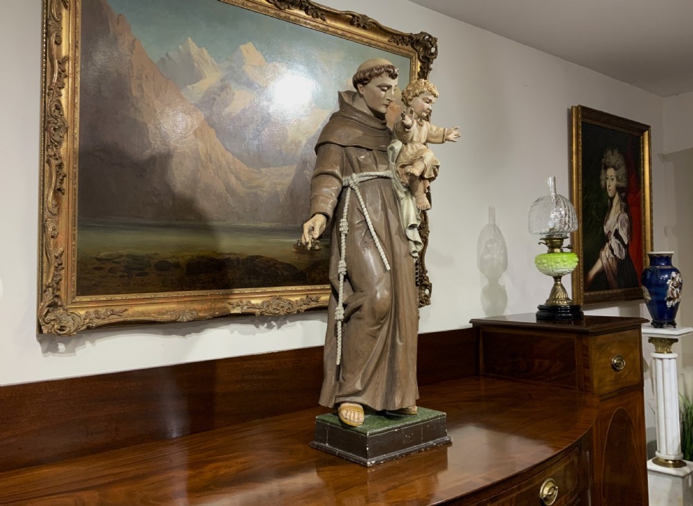 A carved polychrome wood statue depicting a saint in a brown robe holding the infant Jesus. View XXIII