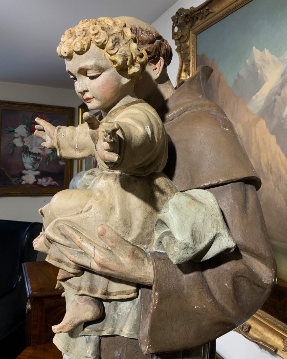 A carved polychrome wood statue depicting a saint in a brown robe holding the infant Jesus. View XXIV
