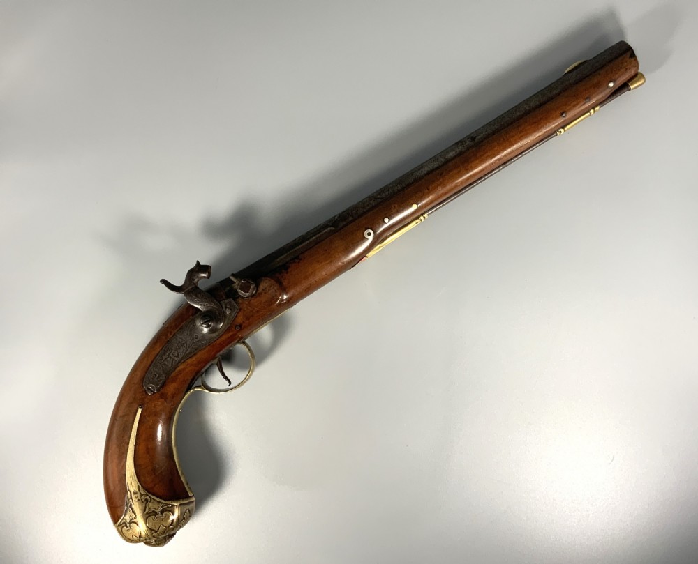 A 19th-century Regency smooth-bore percussion pistol with a carved walnut stock, engraved steel lockwork, and brass fittings.