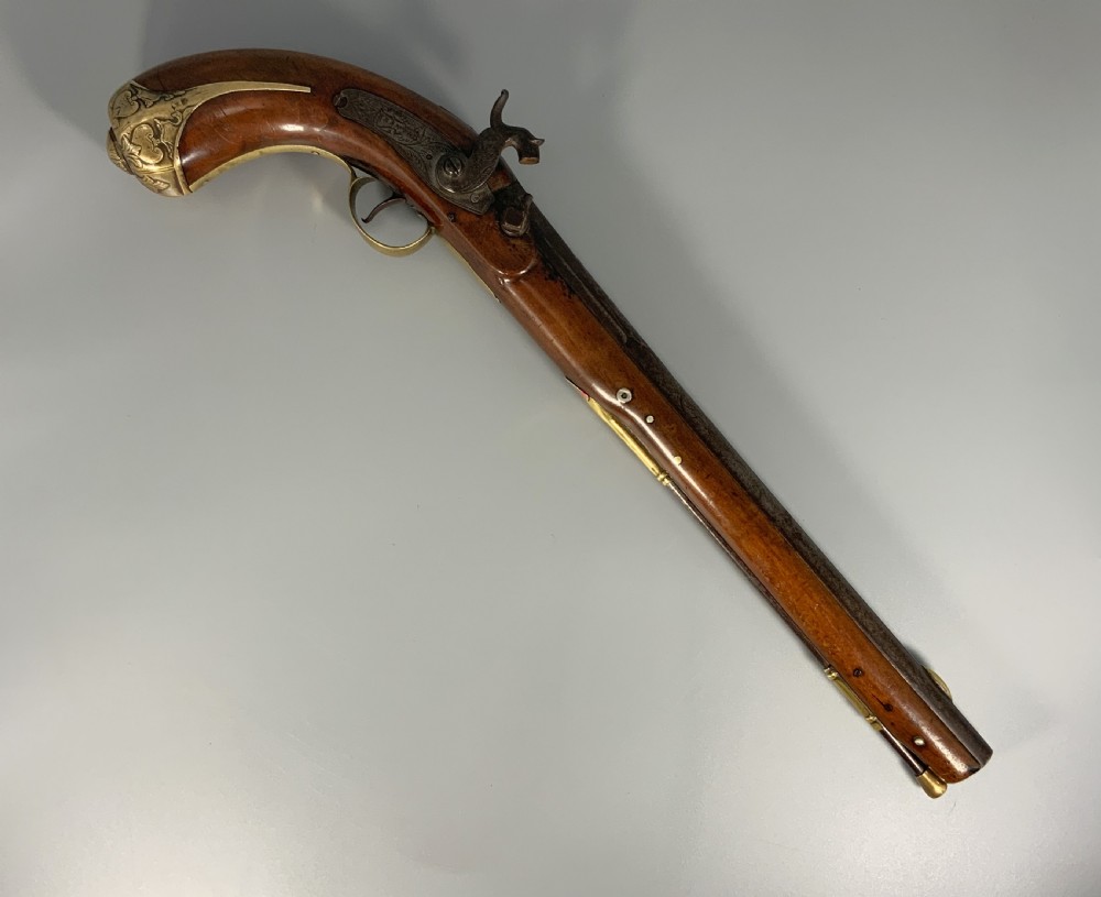 A 19th-century Regency smooth-bore percussion pistol with a carved walnut stock, engraved steel lockwork, and brass fittings. View II
