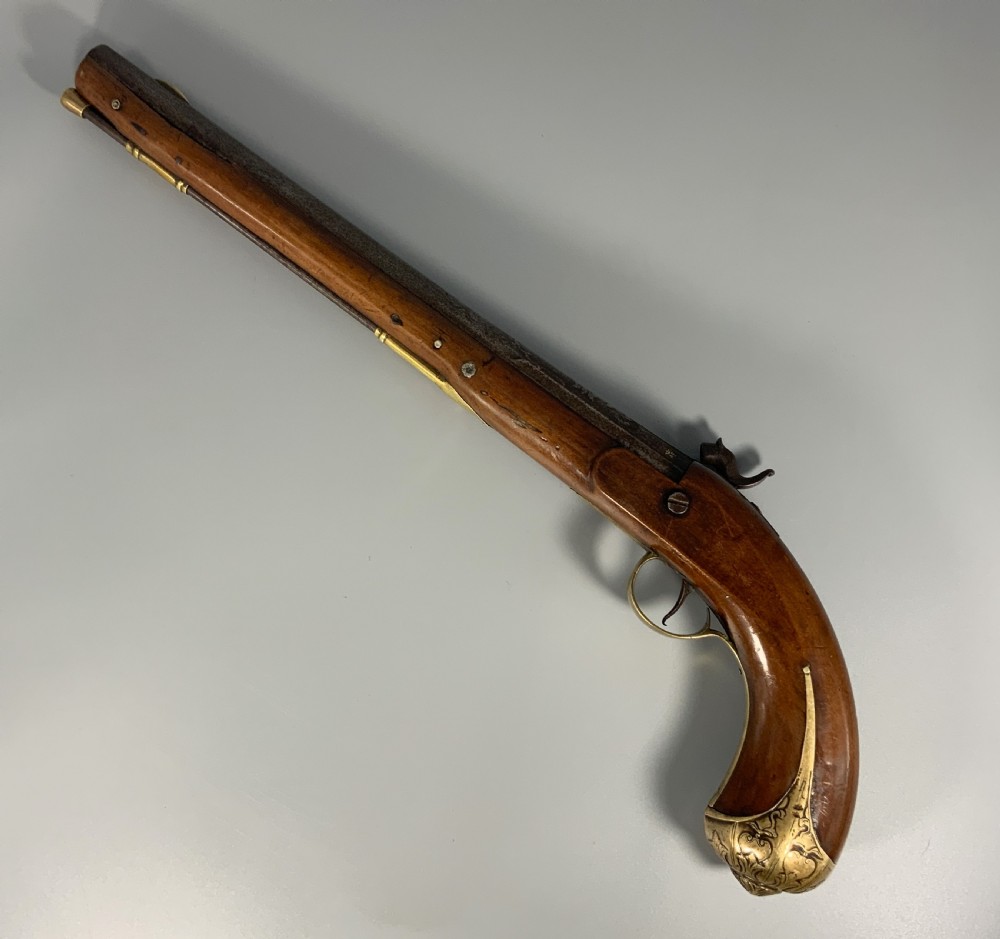 A 19th-century Regency smooth-bore percussion pistol with a carved walnut stock, engraved steel lockwork, and brass fittings. View IV