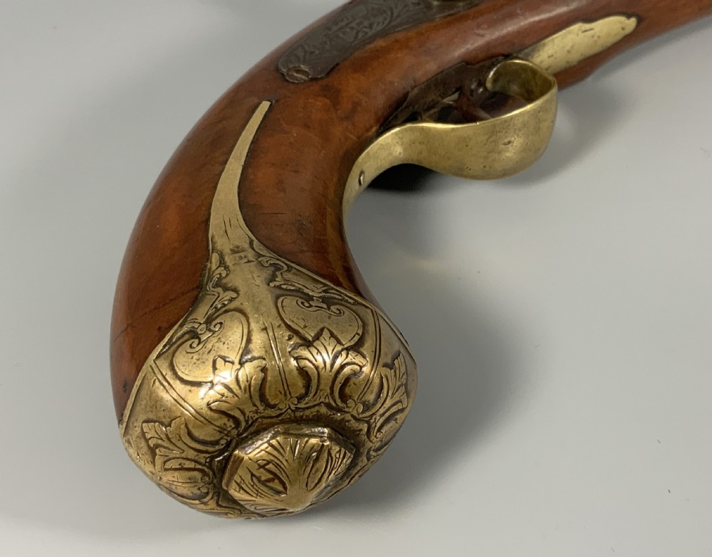 A 19th-century Regency smooth-bore percussion pistol with a carved walnut stock, engraved steel lockwork, and brass fittings. View VI