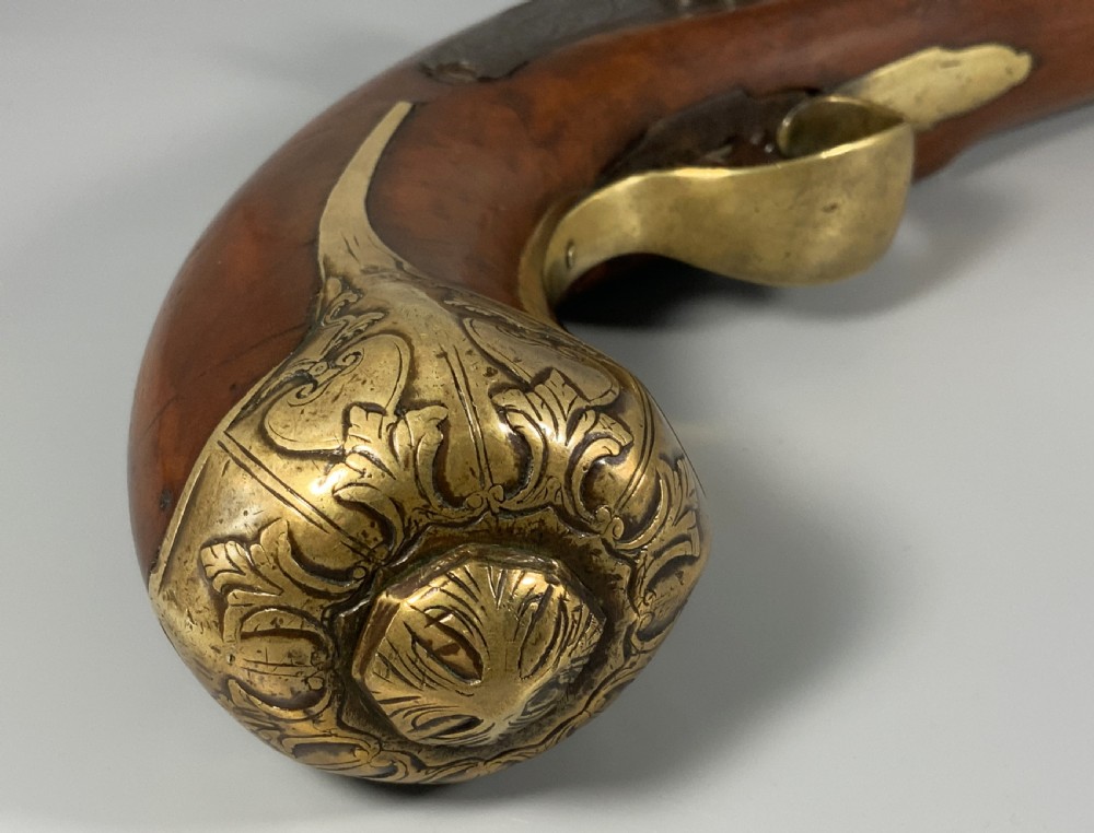 A 19th-century Regency smooth-bore percussion pistol with a carved walnut stock, engraved steel lockwork, and brass fittings. View VII