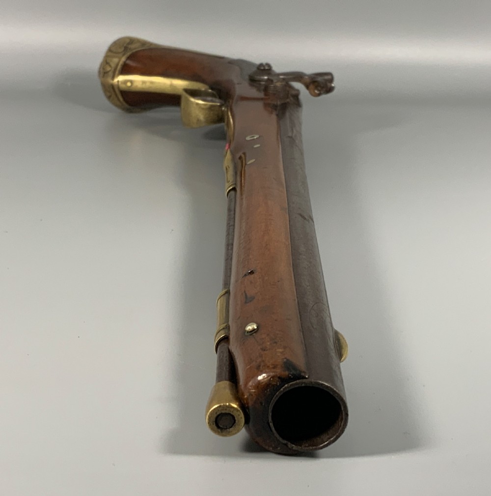 A 19th-century Regency smooth-bore percussion pistol with a carved walnut stock, engraved steel lockwork, and brass fittings. View IX