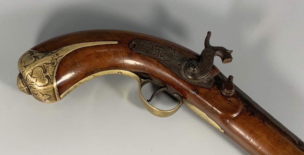A 19th-century Regency smooth-bore percussion pistol with a carved walnut stock, engraved steel lockwork, and brass fittings. View XI
