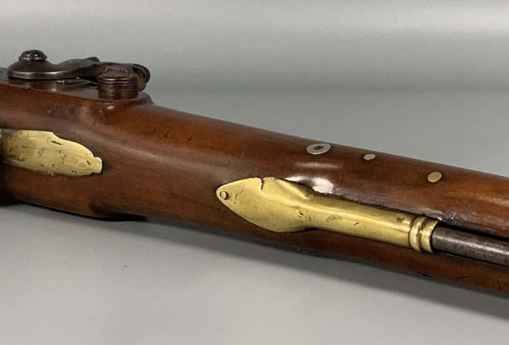 A 19th-century Regency smooth-bore percussion pistol with a carved walnut stock, engraved steel lockwork, and brass fittings. View XIII