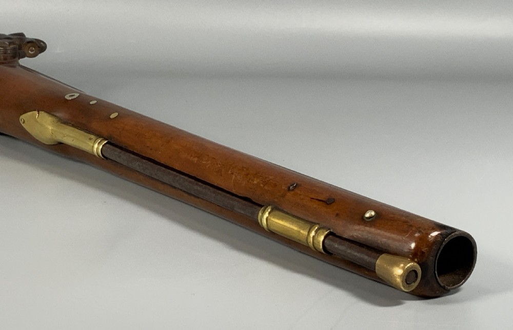 A 19th-century Regency smooth-bore percussion pistol with a carved walnut stock, engraved steel lockwork, and brass fittings. View XIV