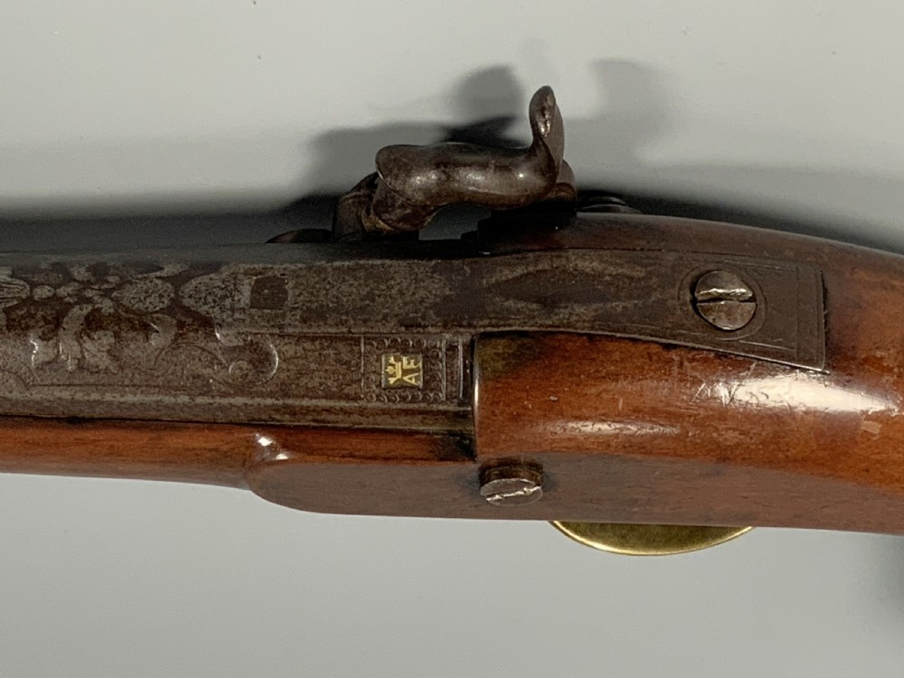 A 19th-century Regency smooth-bore percussion pistol with a carved walnut stock, engraved steel lockwork, and brass fittings. View XV