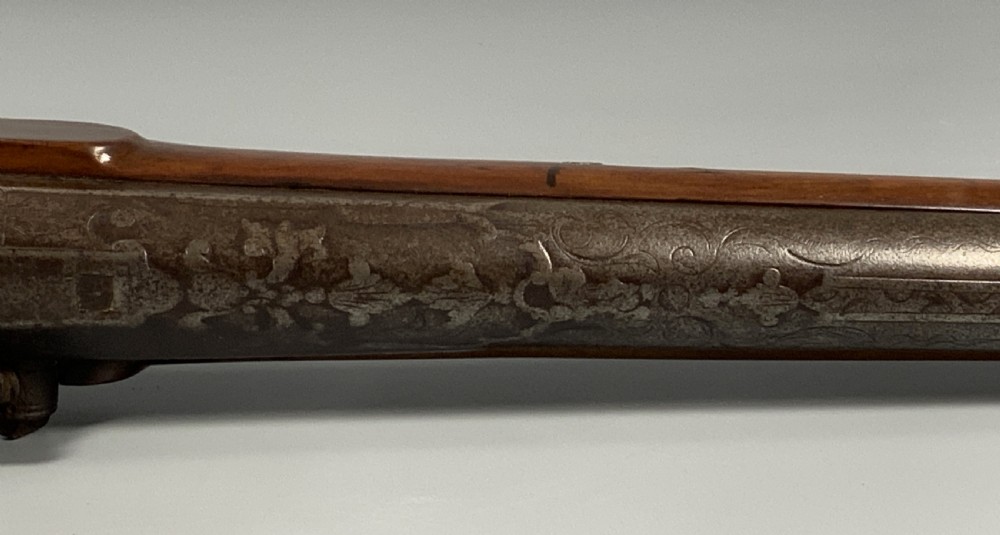 A 19th-century Regency smooth-bore percussion pistol with a carved walnut stock, engraved steel lockwork, and brass fittings. View XVI
