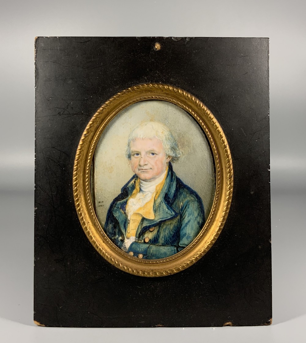 An oval Georgian portrait miniature of a gentleman with grey hair, wearing a blue coat and yellow waistcoat, set within a gilded rope-twist frame. View II