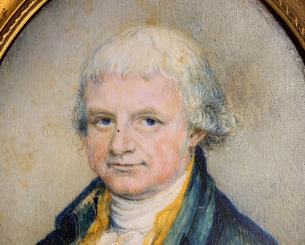 An oval Georgian portrait miniature of a gentleman with grey hair, wearing a blue coat and yellow waistcoat, set within a gilded rope-twist frame. View VI