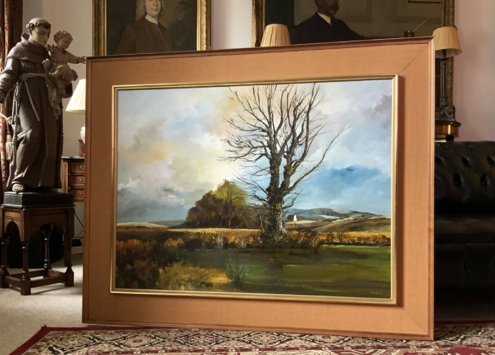 A large mid-century framed oil painting on canvas depicting a rural autumn landscape with a central bare tree near a body of water.