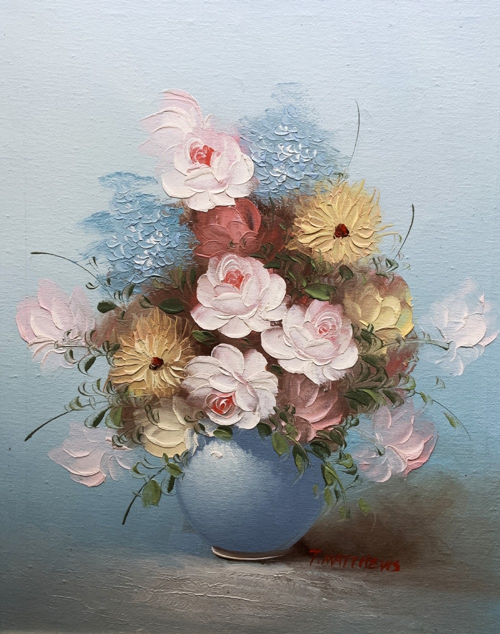 A framed post-war floral still life oil painting depicting pink, yellow, and blue flowers in a rounded blue vase within a gilt wooden frame. View II