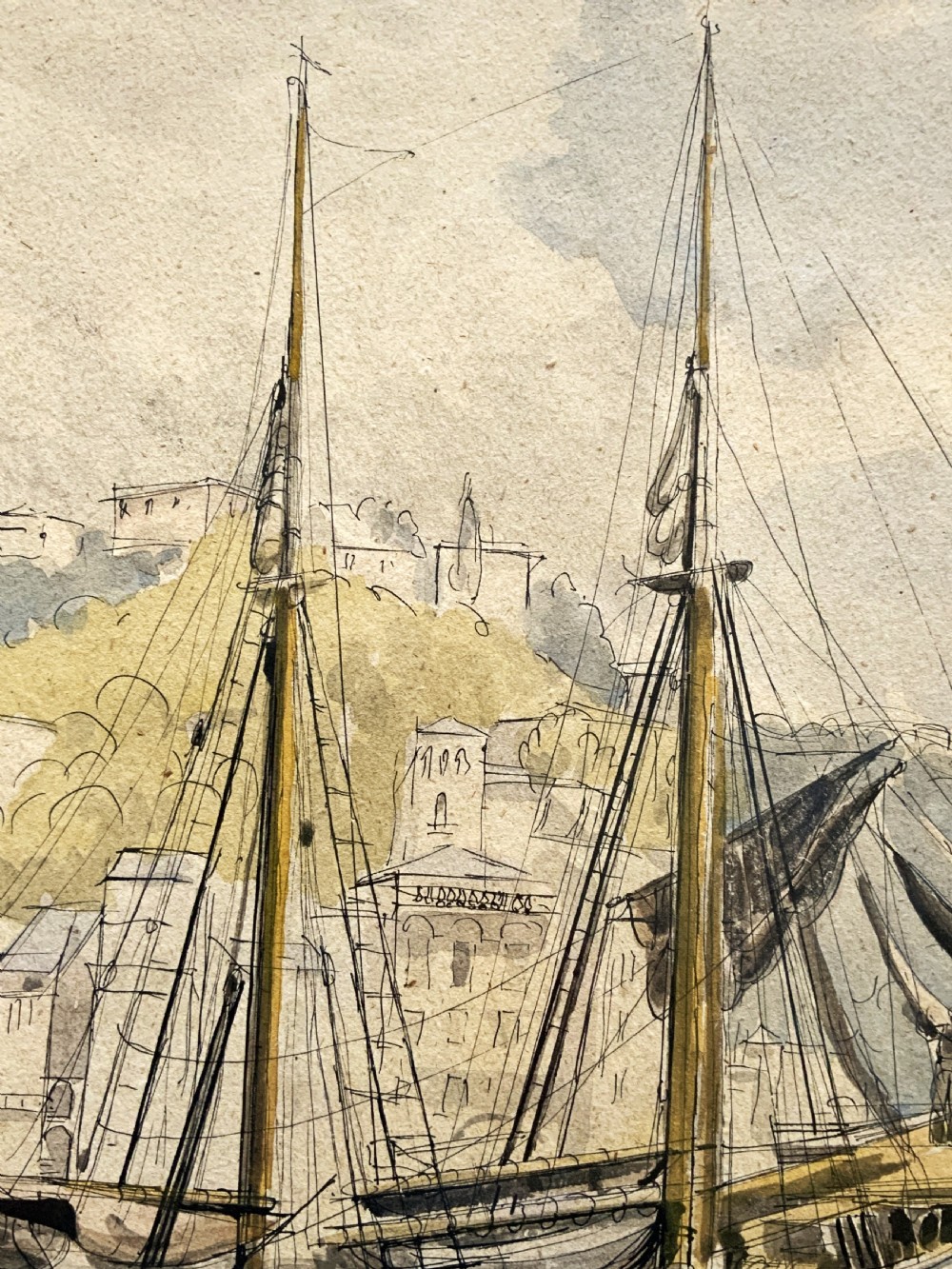 A framed 19th-century watercolour painting depicting a two-masted sailing yacht moored in a coastal harbour in front of a hillside town. View X