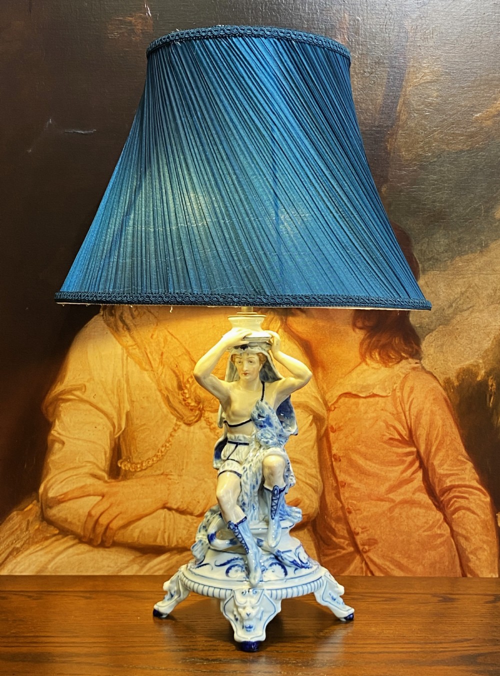 An Art Deco blue and white porcelain table lamp featuring a sculpted male figure on a decorative pedestal with a twin brass light socket stem. View II