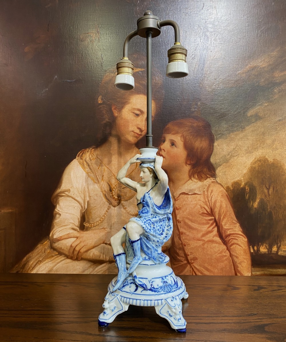 An Art Deco blue and white porcelain table lamp featuring a sculpted male figure on a decorative pedestal with a twin brass light socket stem. View III