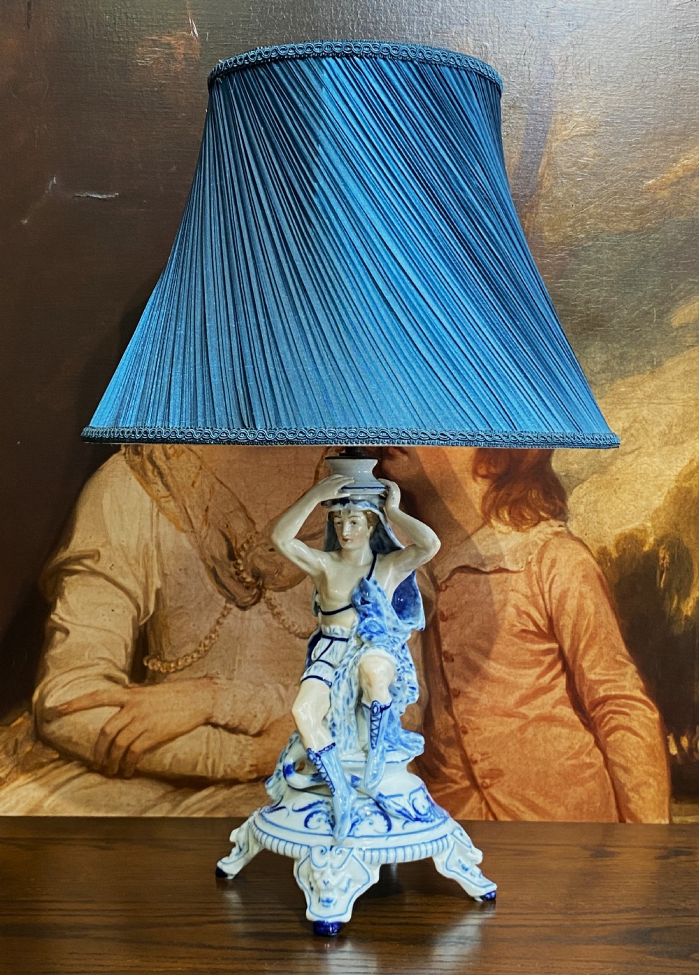An Art Deco blue and white porcelain table lamp featuring a sculpted male figure on a decorative pedestal with a twin brass light socket stem. View VI