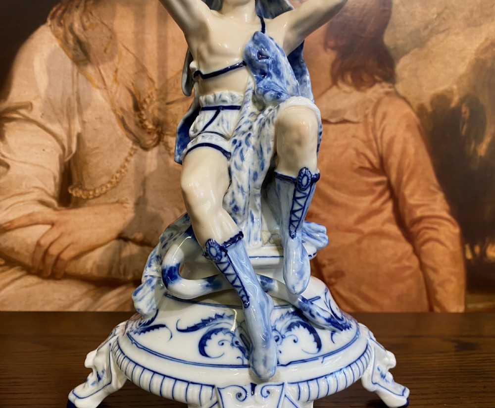 An Art Deco blue and white porcelain table lamp featuring a sculpted male figure on a decorative pedestal with a twin brass light socket stem. View IX